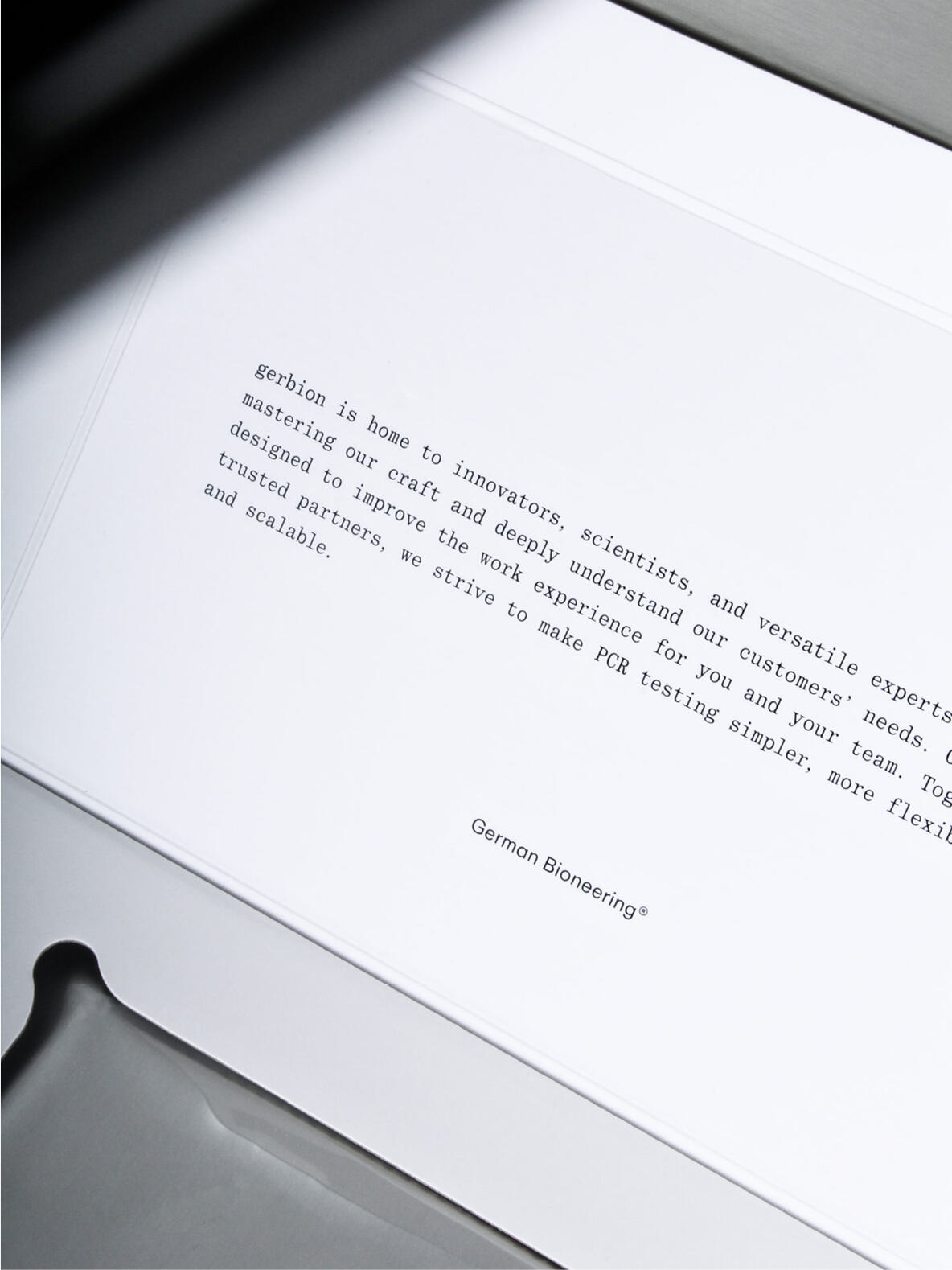 Nahaufnahme des geöffneten Deckels einer gerbion-Verpackung. Auf der Innenseite ist ein zentral platzierter Text in Monospace-Schrift zu lesen, der das Selbstverständnis und die Zielsetzung des Unternehmens beschreibt. Unten steht die Wortmarke „German Bioengineering®“. Die Gestaltung wirkt klar, technisch und hochwertig.